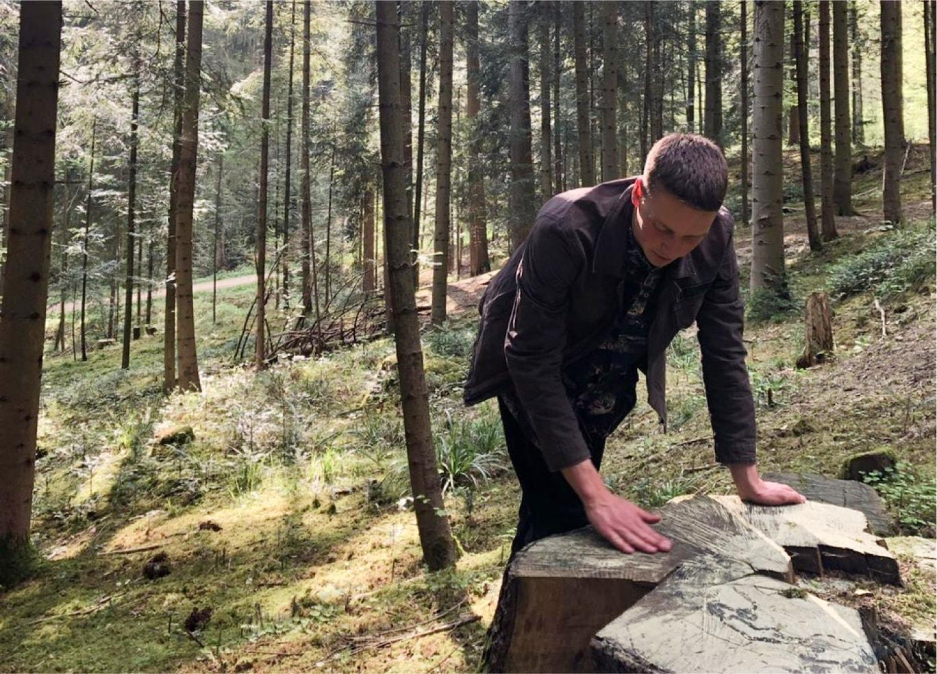 Guy is working with wood in the forest